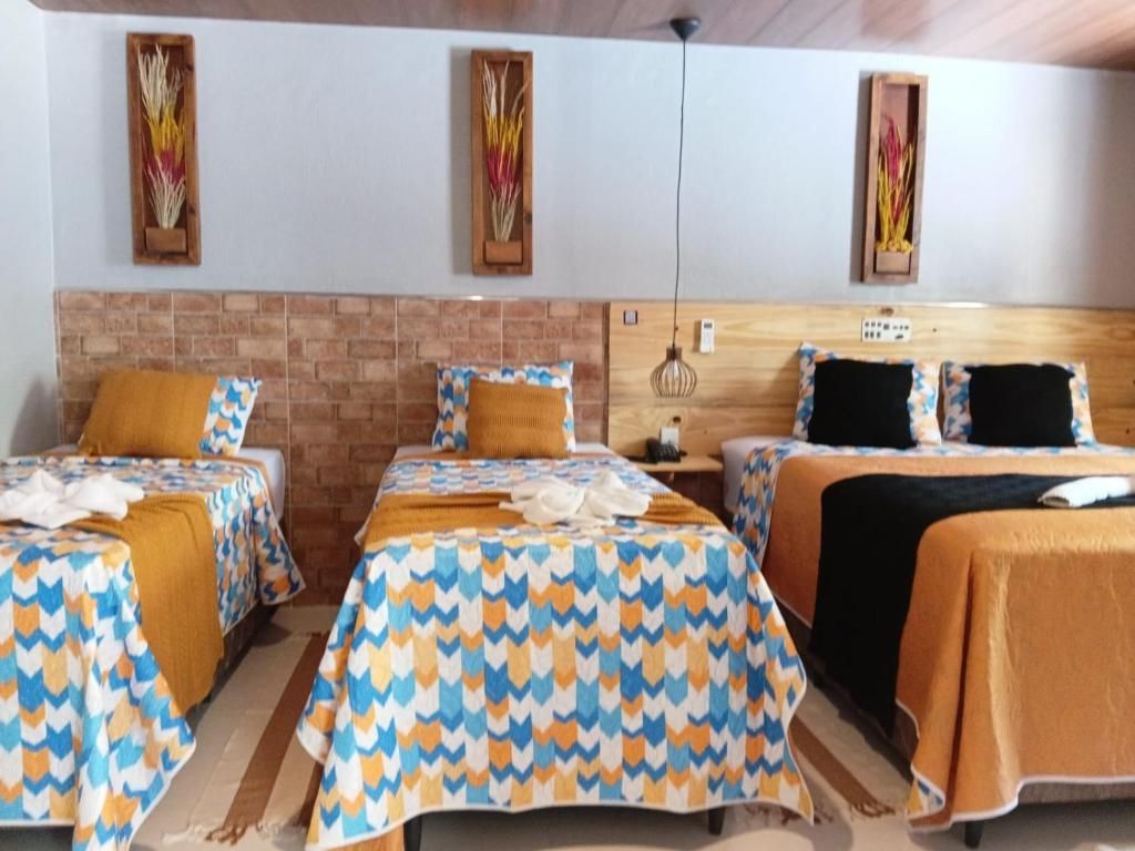 Habitación de hotel con dos camas, una pared de ladrillo decorativa y un cabecero de madera.