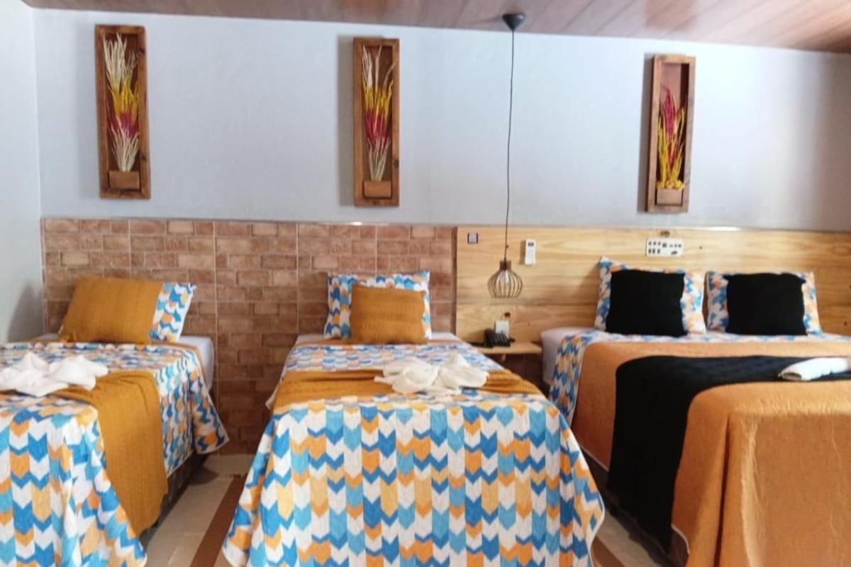 Habitación de hotel con dos camas, una pared de ladrillo decorativa y un cabecero de madera.