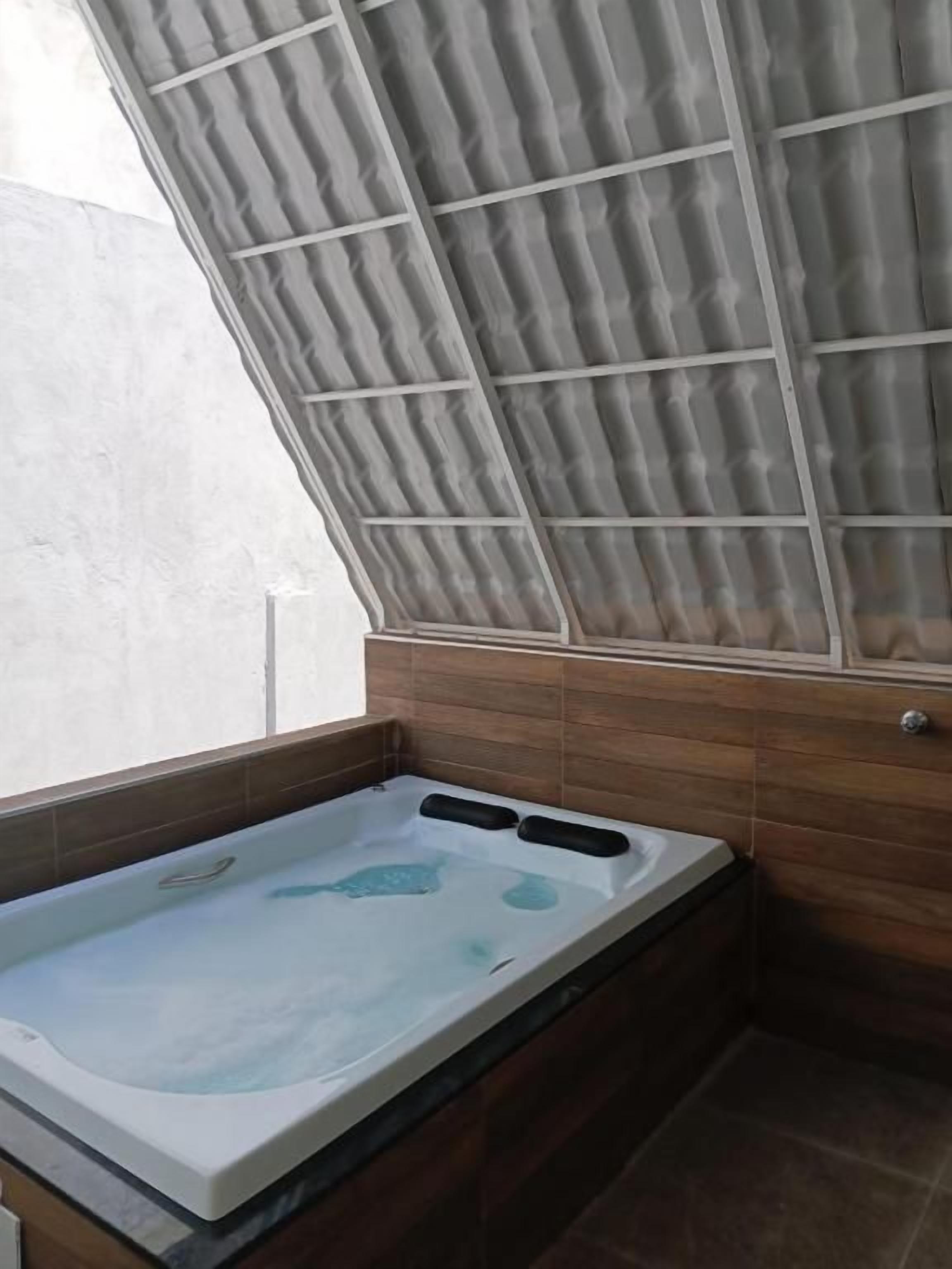 A spa area with a hot tub, wooden paneling, and a metal ceiling structure.
