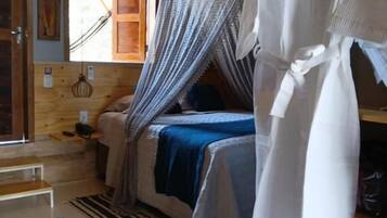 Quarto com cama, roupão pendurado, cadeira e janela.