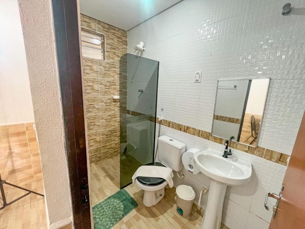 Un baño con inodoro, lavabo y cabina de ducha con mampara de vidrio.