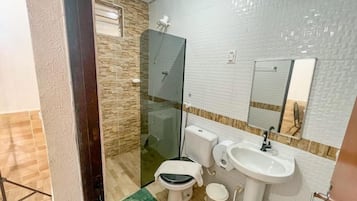 Un baño con inodoro, lavabo y cabina de ducha con mampara de vidrio.