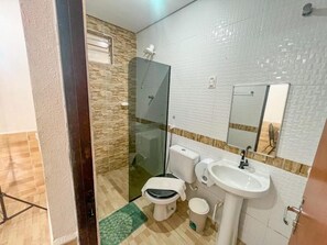Un baño con inodoro, lavabo y cabina de ducha con mampara de vidrio.