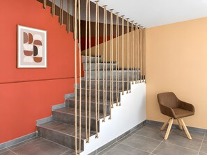 Een trap met een touwbalk, een lijstwerk abstract kunstwerk en een bruine stoel.