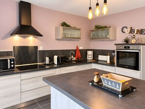 Een moderne keuken met een ingebouwde magnetron, waterkoker en koffiezetapparaat.