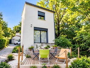 A modern two-story building with a deck, outdoor seating, and a car parked nearby. - Holiday Home 'Cozy House with Outdoor Area' with Mountain View, Private Terrace and Wi-Fi (Anduze)