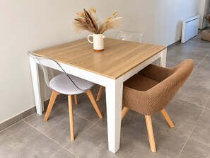 A dining table with a white pitcher and dried flowers, a white chair, and a brown chair with wooden legs. - Holiday Home 'Cozy House with Outdoor Area' with Mountain View, Private Terrace and Wi-Fi (Anduze)