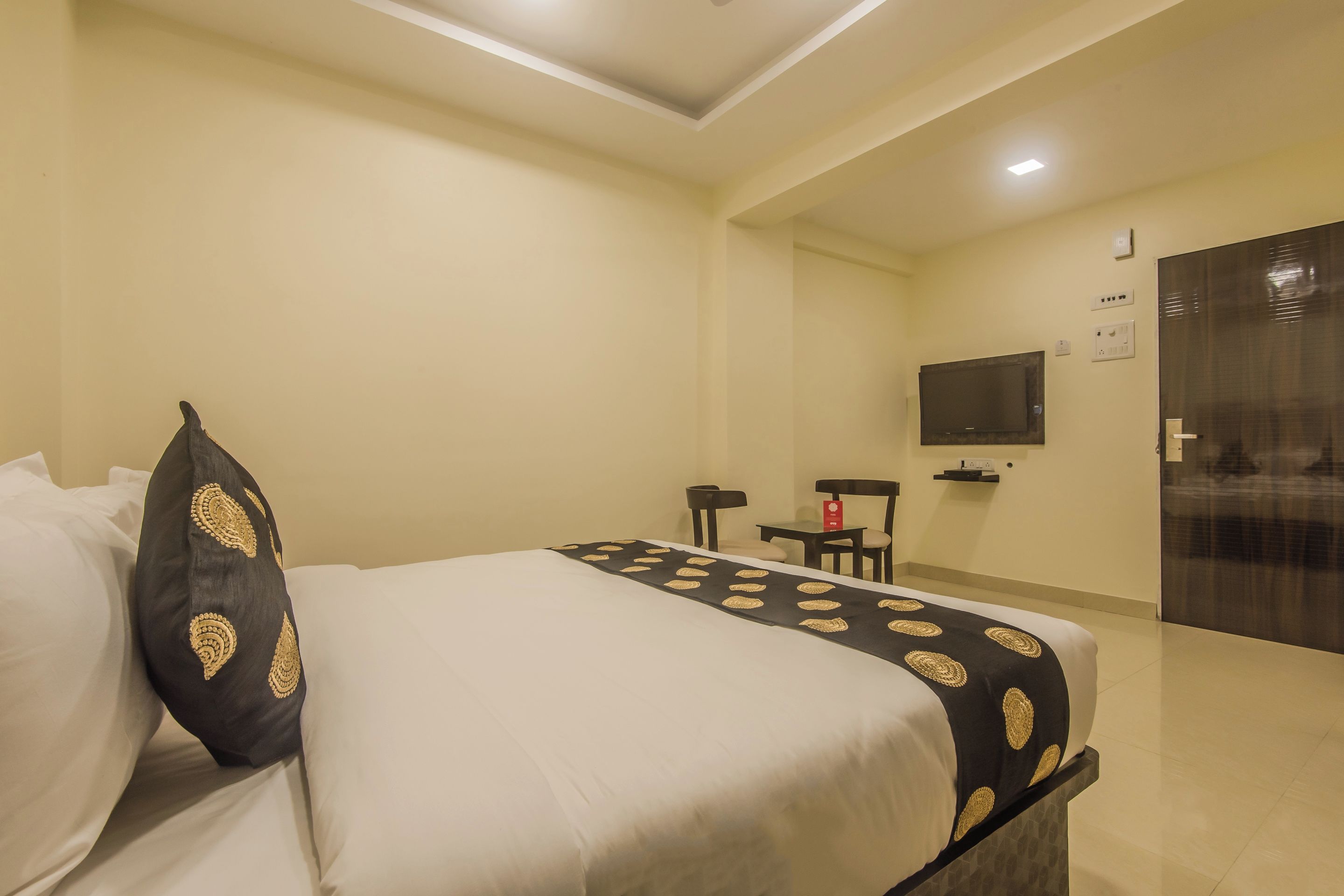 Habitació d'hotel amb un llit, una televisió, un escriptori i una porta.