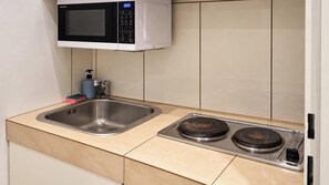 A kitchen with a stainless steel sink, a microwave, and a gas stove. - Live a Little Longer in Vienna 1BR (Vienna)