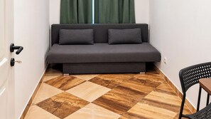 A room with a sofa, a chair, and a patterned floor. - Live a Little Longer in Vienna 1BR (Vienna)