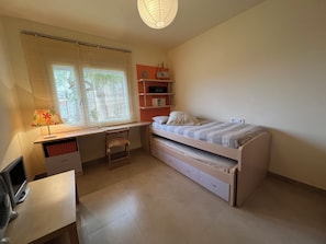 A bedroom with a bed, desk, chair, and a shelf with books. - Vrbo Property (AN)