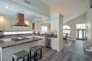 A spacious kitchen with a large island, built-in appliances, and a view to the dining area.