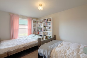 A bedroom with two single beds, a bookshelf, and a window with curtains. - Walkable Fairplay Home w/ Mtn Views! (Fairplay)