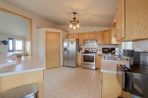 A kitchen with wooden cabinets, stainless steel appliances, a central island, and a chandelier. - Walkable Fairplay Home w/ Mtn Views! (Fairplay)