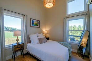 A bedroom with a bed, bedside lamps, a painting, and large windows. - Near Trails & Live Music! Quiet Floyd Gem w/ Views (Floyd)