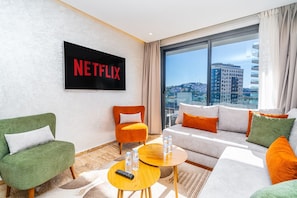 A modern hotel room with a large window, a flat-screen TV, and a sofa. - New luxury apartment near the TGV station (Tanger)