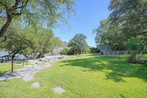 A grassy park area with trees, a stone pathway, and a building in the background. - 2 Boat Docks! Marble Falls Lake Retreat (Marble Falls)