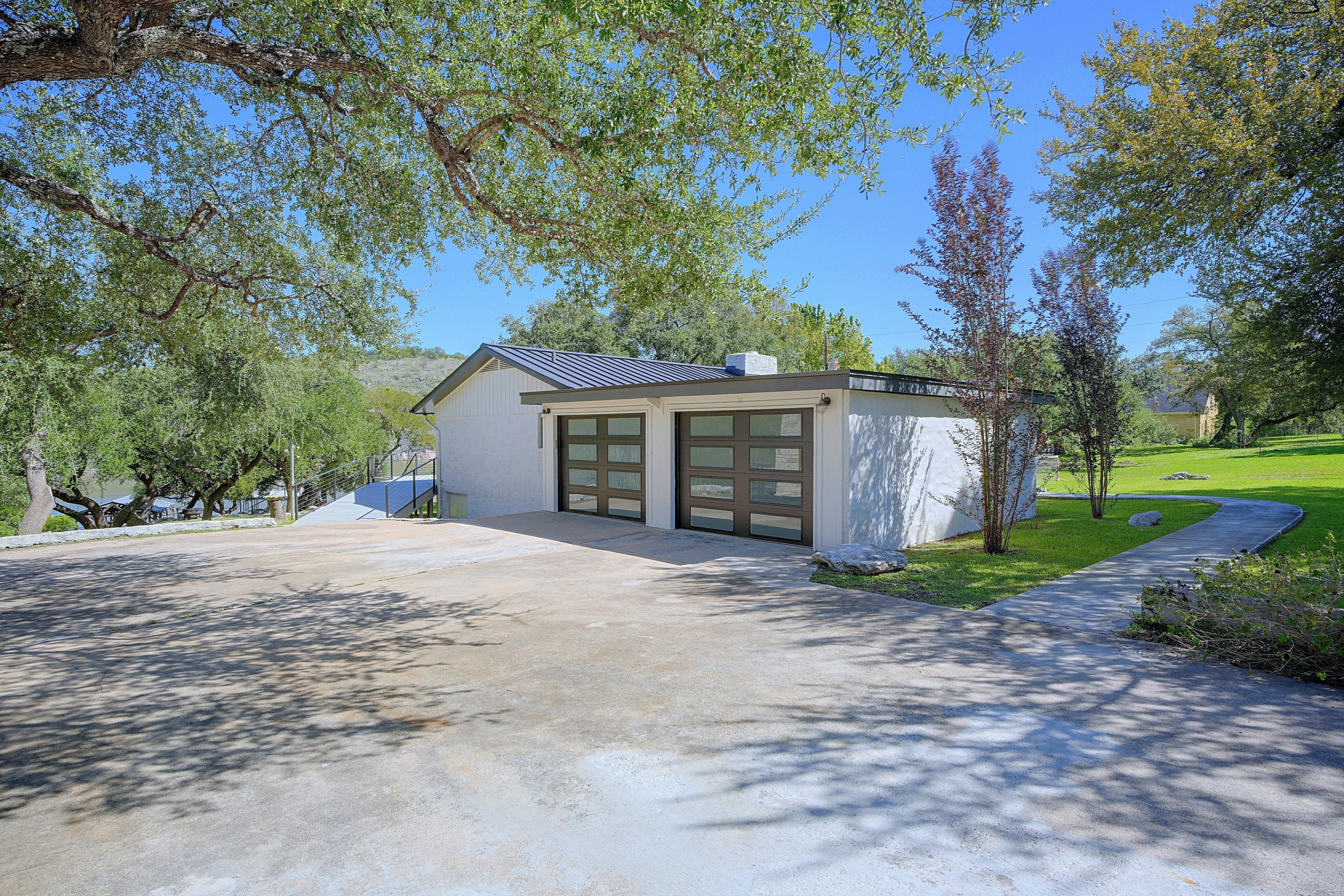 A modern house with a garage, surrounded by trees and a well-maintained lawn.