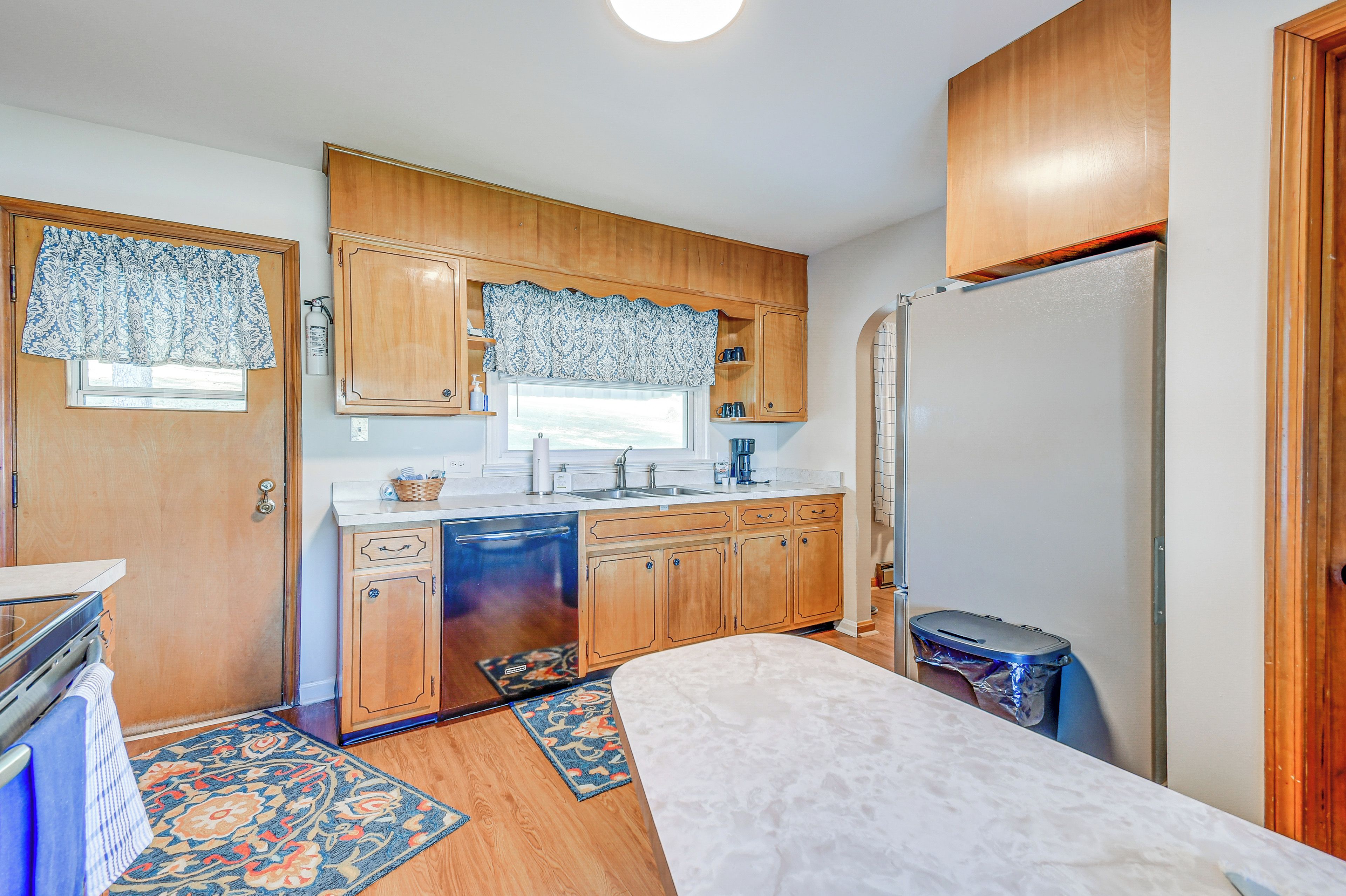 A compact kitchen with wooden cabinets, a built-in dishwasher, and a refrigerator.