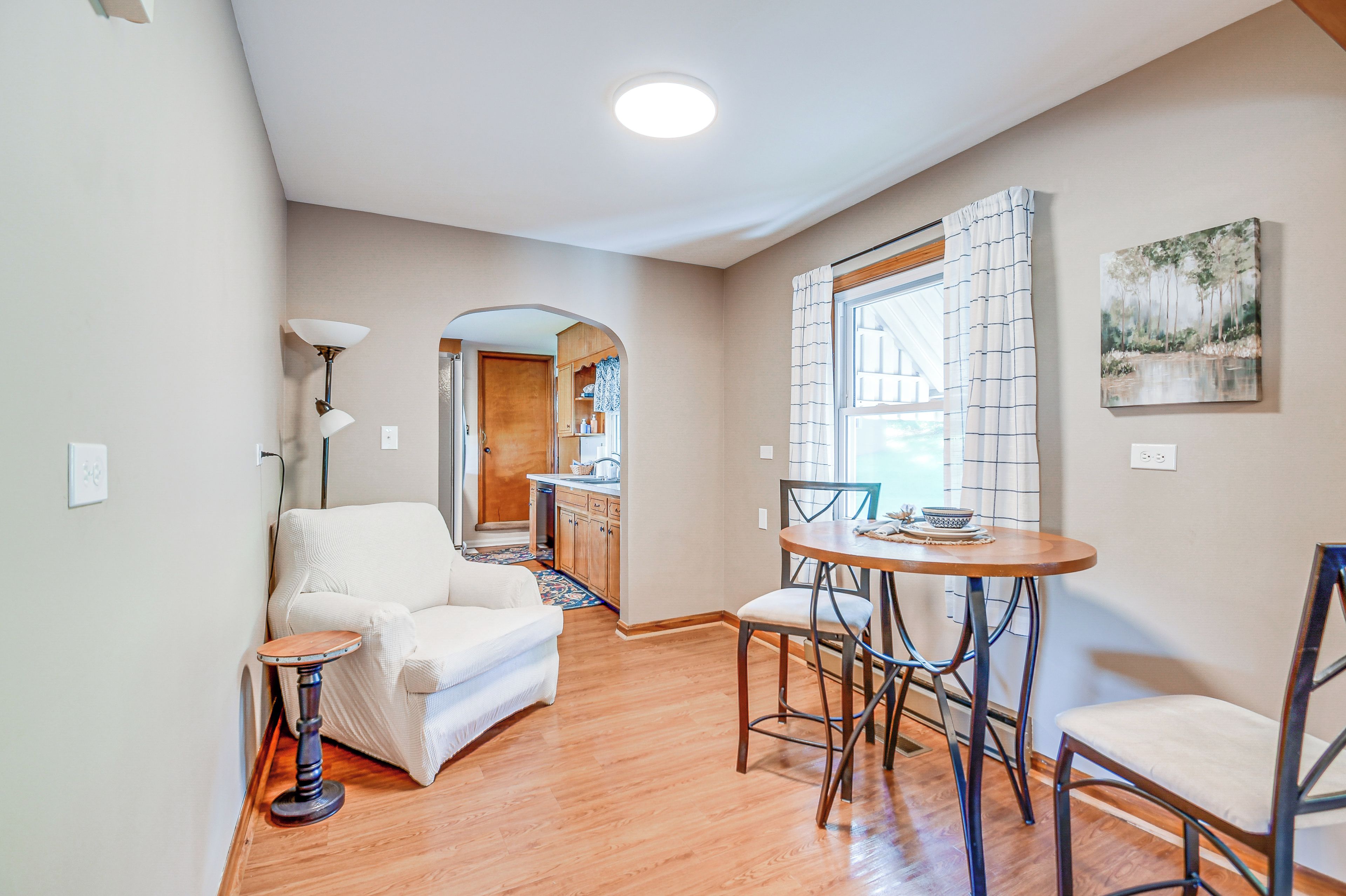 A modern living room with a sofa, a small round table, and a dining area with a chair.