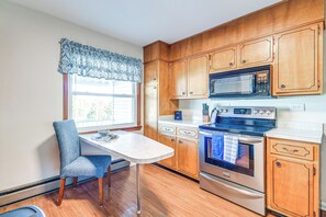 A kitchen with wooden cabinets, a built-in microwave, a stove, and a window with a patterned valance.
