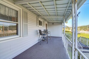 A covered porch with a table and chairs, a view of the outside, and a window with blinds.