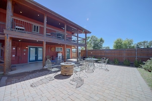 A two-story building with a covered patio area featuring outdoor seating and a fire pit.