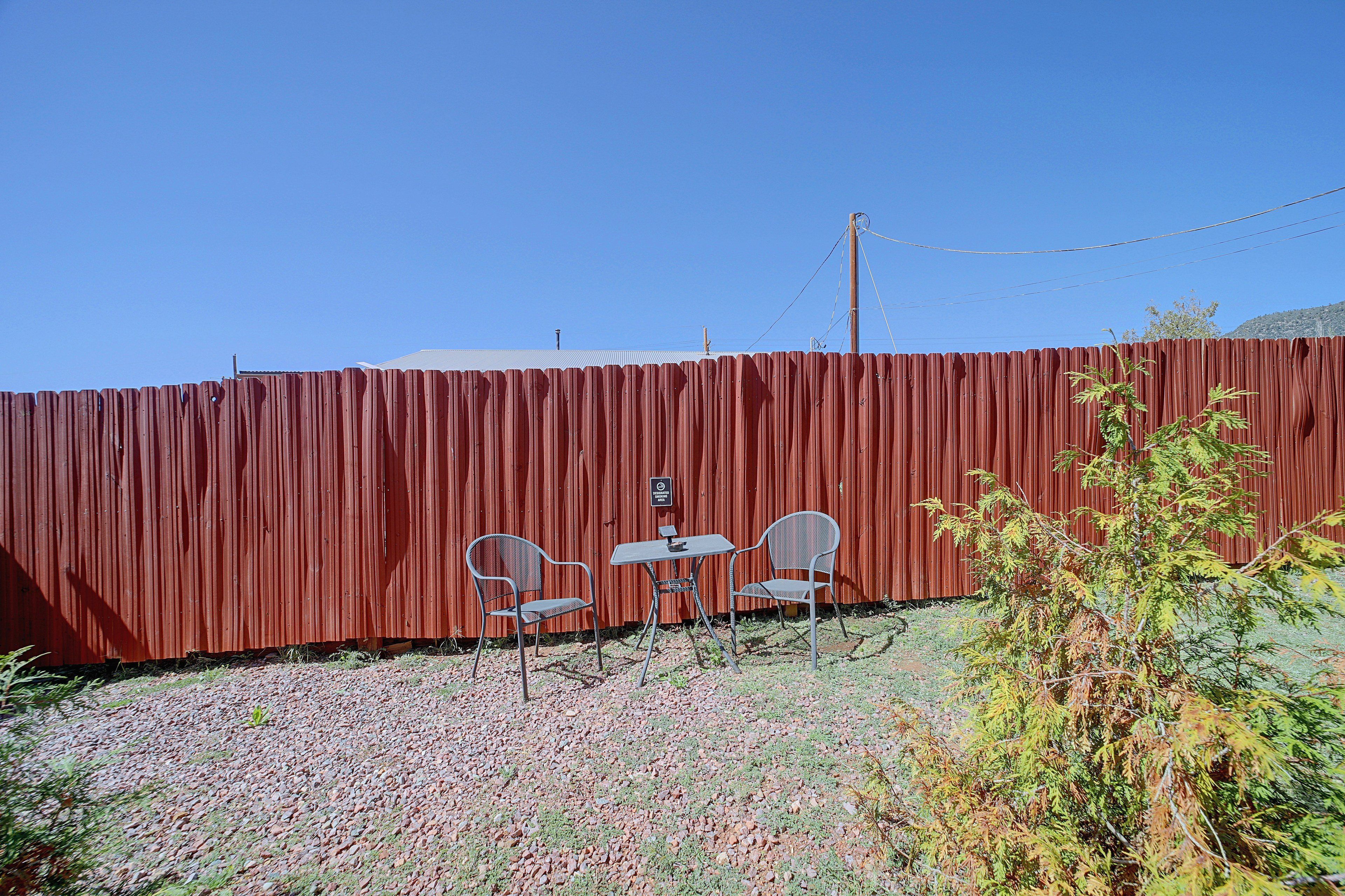 A fenced outdoor area with two metal chairs and a small table.