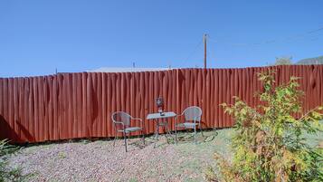 A fenced outdoor area with two metal chairs and a small table.