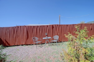 A fenced outdoor area with two metal chairs and a small table.