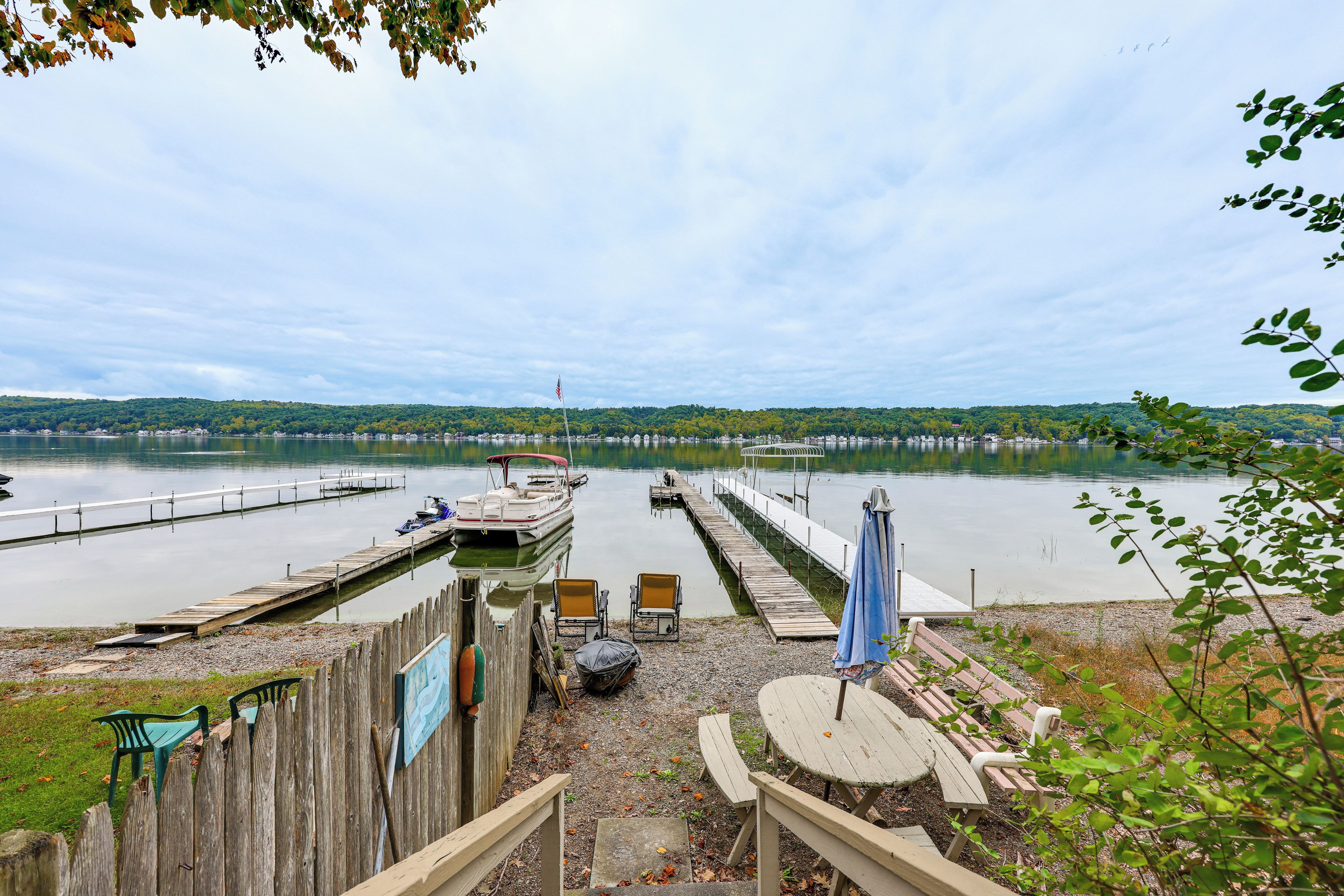A lakeside dock with boats, a picnic table, and a view of the lake and distant hills.