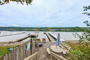 A lakeside dock with boats, a picnic table, and a view of the lake and distant hills.
