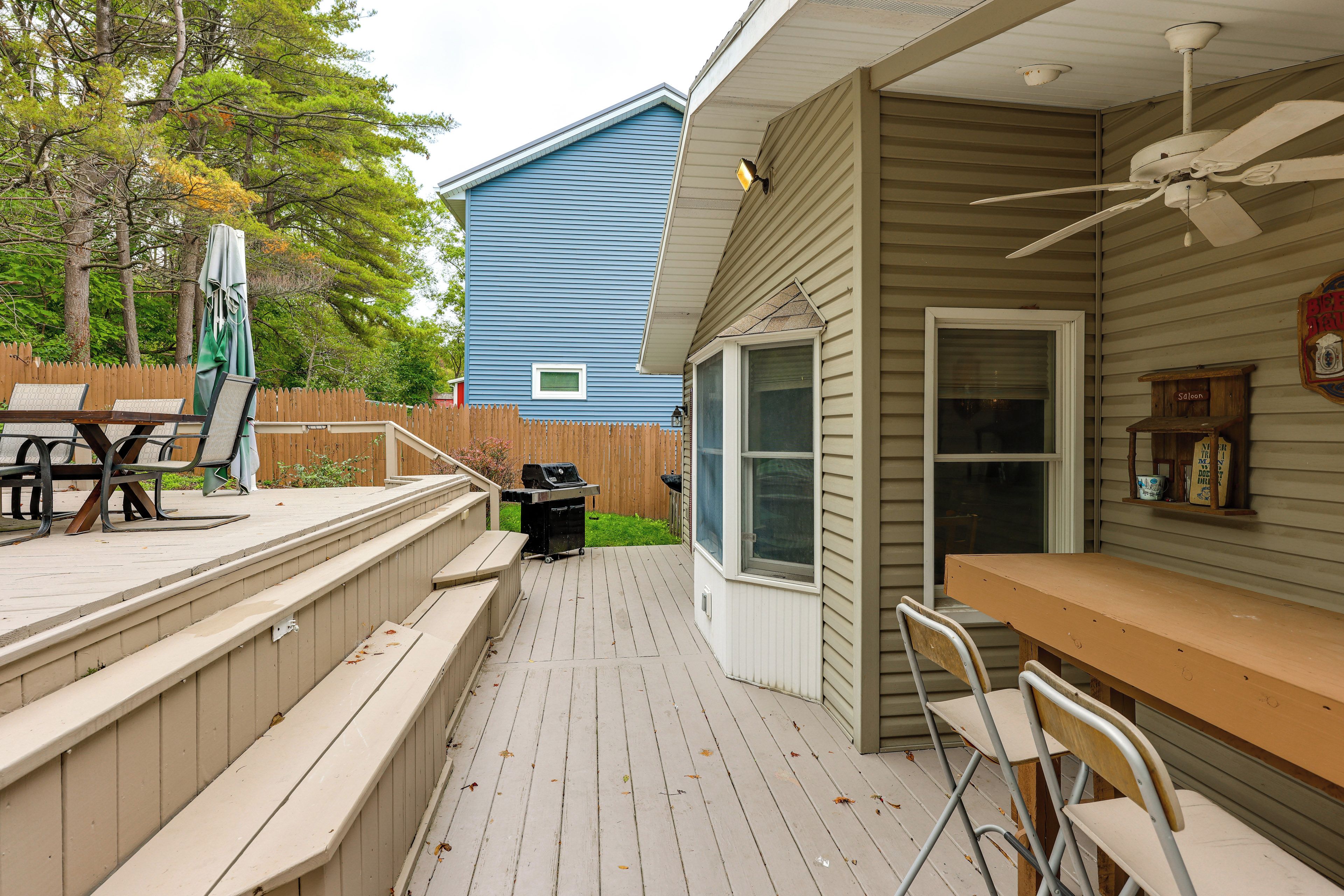 A deck with a table and chairs, a barbecue grill, and a wooden fence.
