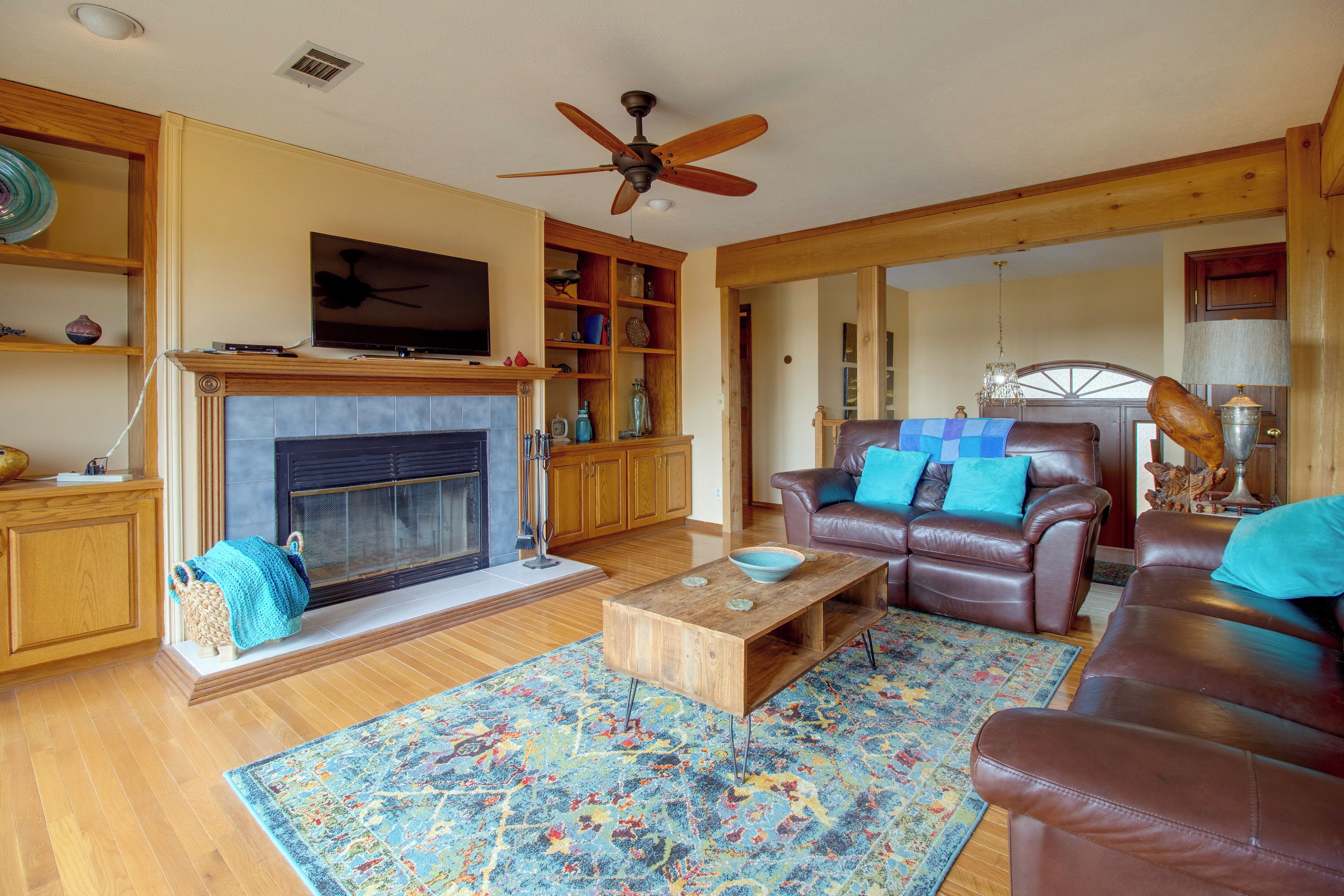 A living room with a fireplace, leather sofa, wooden coffee table, and a ceiling fan.