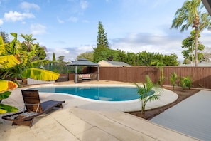 A backyard with a swimming pool, a covered seating area, and a wooden fence. - Private Pool Oasis: Modern 3br/2ba, Sleeps 8 (San Diego)