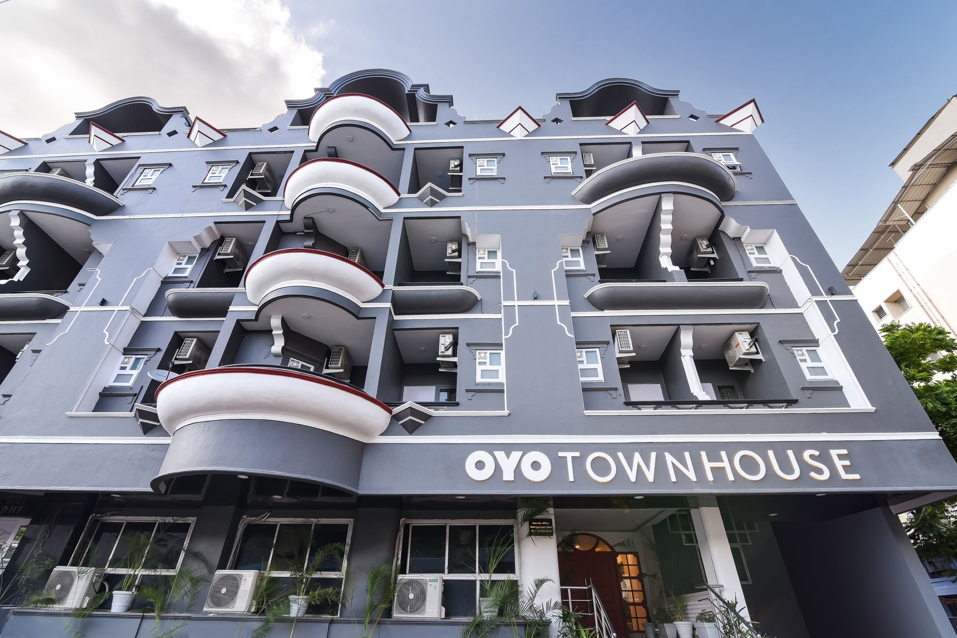 A modern building with balconies, air conditioning units, and a sign reading 'OYO TOWNHOUSE'.