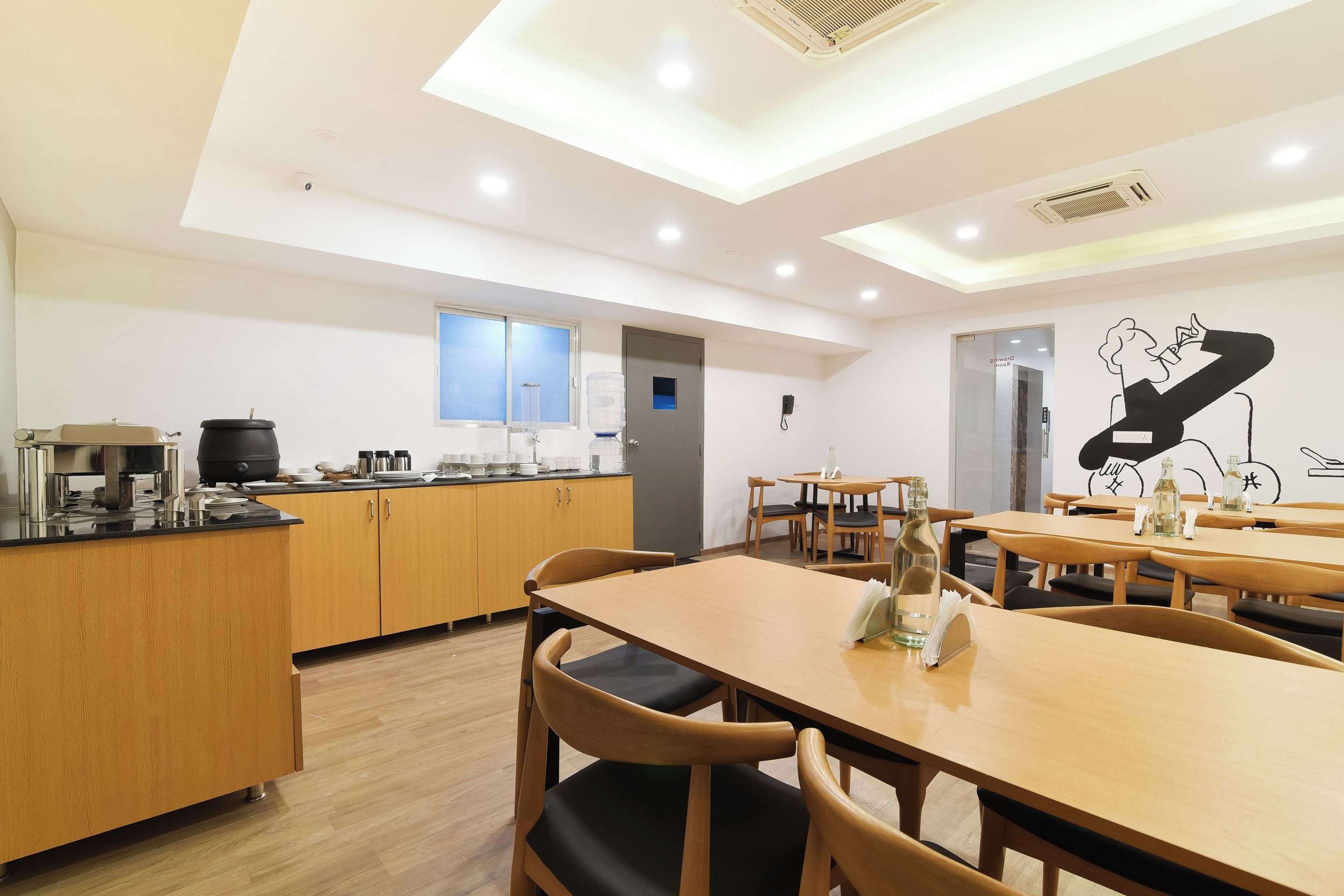 A modern kitchen with wooden cabinets, a countertop with appliances, and a dining area with wooden tables and chairs.