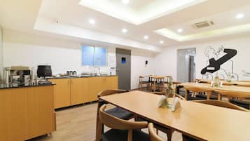A modern kitchen with wooden cabinets, a countertop with appliances, and a dining area with wooden tables and chairs.