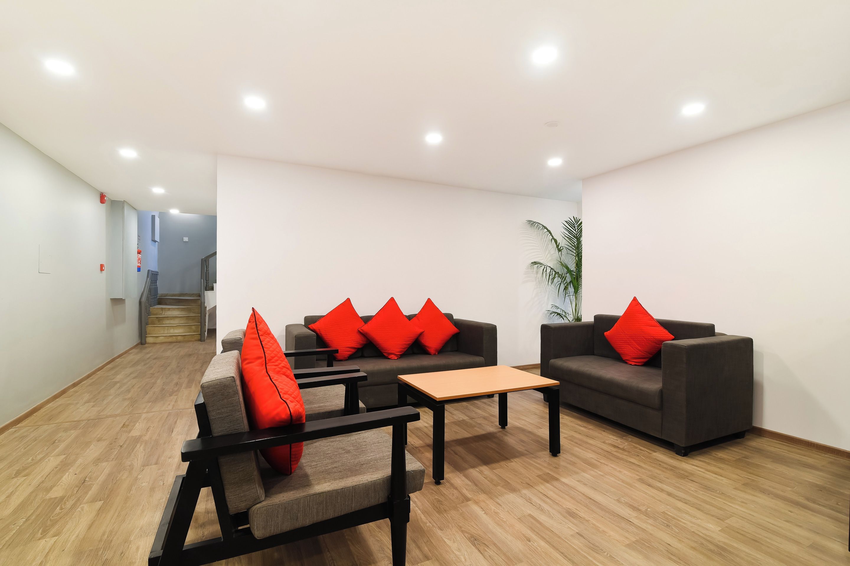 A modern lounge area with sofas, a coffee table, and a staircase in the background.