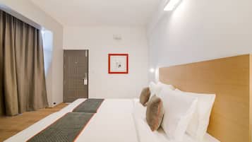 A hotel room with a bed, a door, a light switch, and a wall-mounted light fixture.