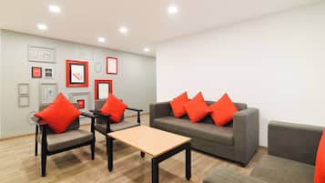 A modern living room with grey sofas, red cushions, and a wooden coffee table.