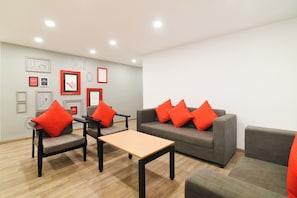 A modern living room with grey sofas, red cushions, and a wooden coffee table. - Townhouse Srm Kuppakonam Pudur (Coimbatore)