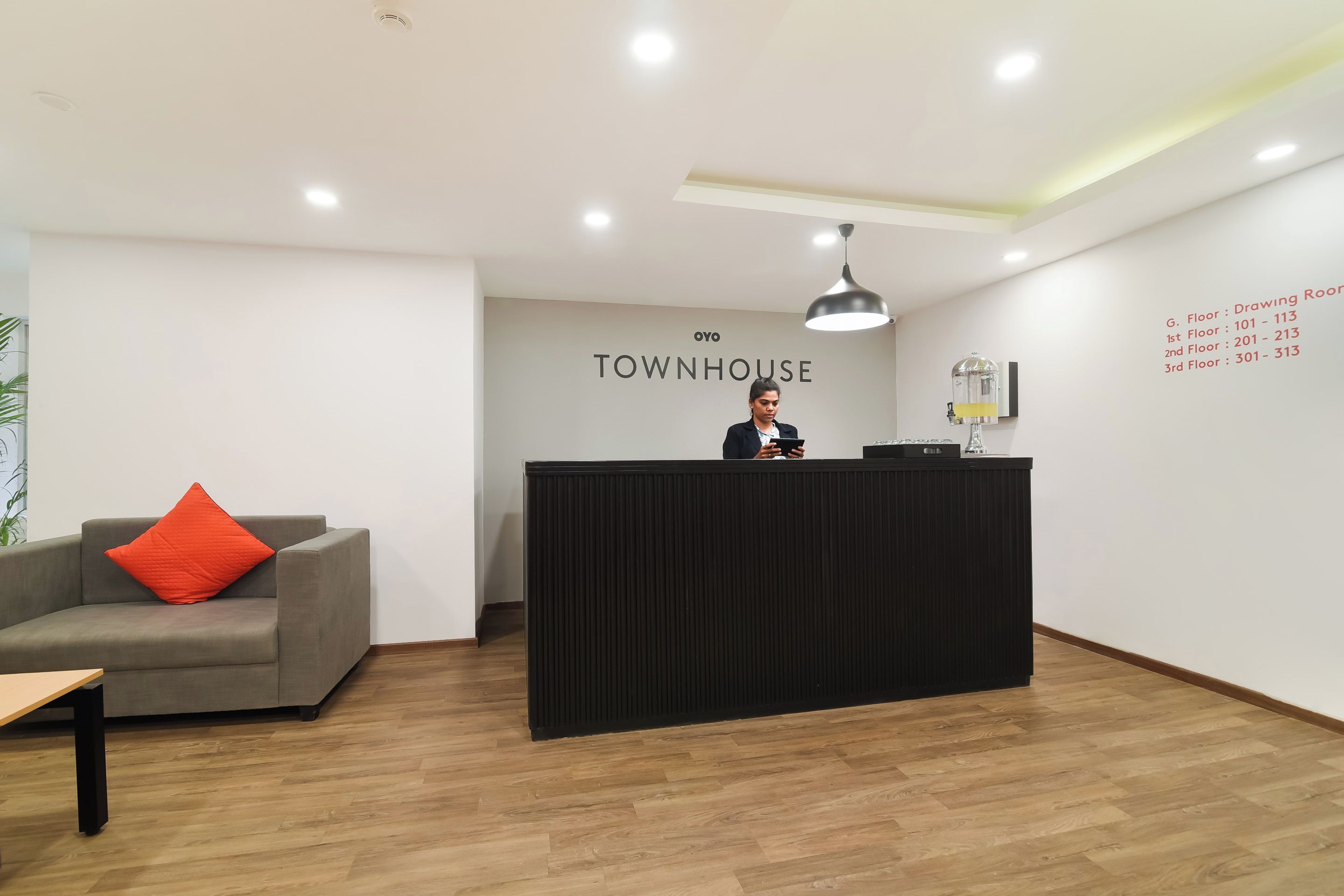 Un comptoir d’accueil avec une enseigne indiquant « TOWNHOUSE » et une liste des numéros d’étage affichée sur le mur.