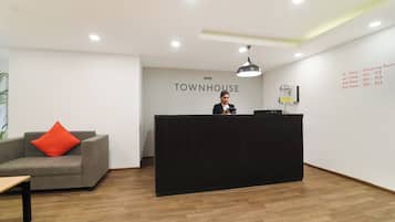 Un comptoir d’accueil avec une enseigne indiquant « TOWNHOUSE » et une liste des numéros d’étage affichée sur le mur.