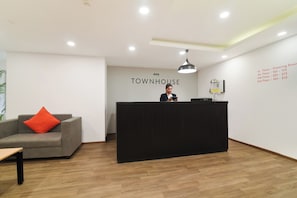 Un mostrador de recepción con un cartel que dice 'TOWNHOUSE' y una lista de números de piso en la pared.