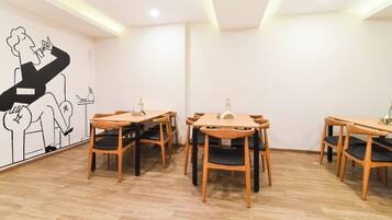 A dining area with wooden tables and chairs, a wall mural, and an air conditioning unit on the ceiling.