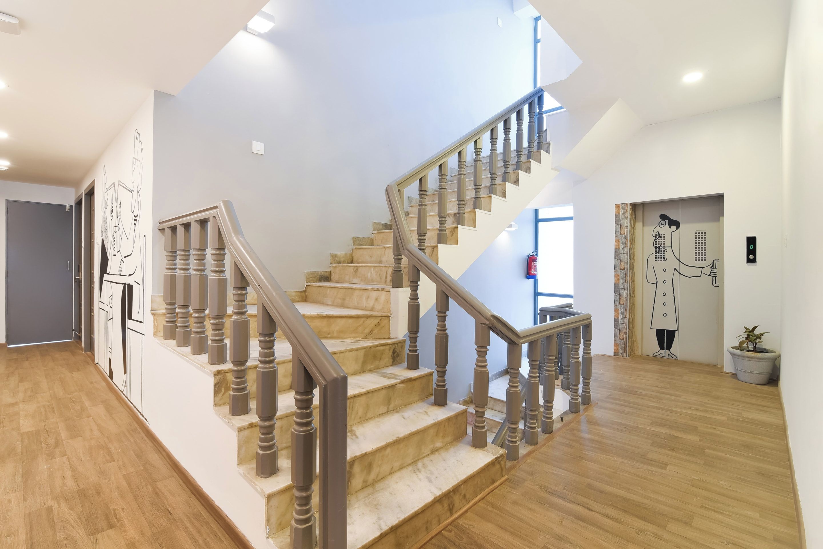 A staircase with wooden steps and balusters, leading to a landing with a door and a wall-mounted artwork.