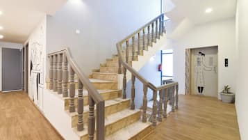 A staircase with wooden steps and balusters, leading to a landing with a door and a wall-mounted artwork.