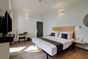 A hotel room with a bed, bedside table, chair, desk, and a TV. - Townhouse Srm Kuppakonam Pudur (Coimbatore)