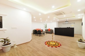 A modern hotel lobby with a reception desk, seating area, and decorative elements like a mandala rug. - Townhouse Srm Kuppakonam Pudur (Coimbatore)